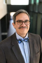 older hispanic man with mustache wearing glasses and a bowtie