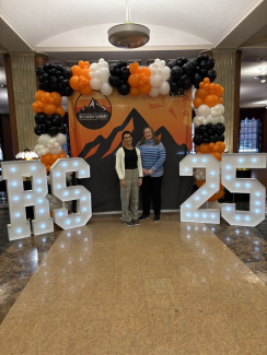 orange and black backdrop with 2 women standing in front