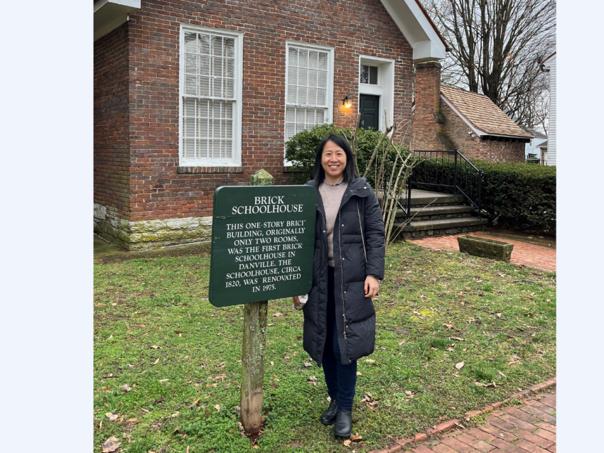 casual photo of Qingfang Liang in front of schoolhouse in KY