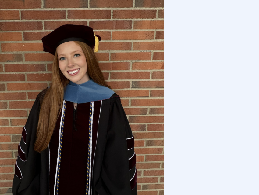 red headed young woman in black doctorate regalia