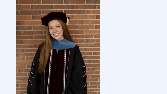 red headed young woman in black doctorate regalia