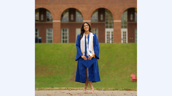 girl in blue graduation gown in front of brick arches