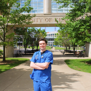 Photo of Shane: young, tall, brunette, in royal blue scrubs standing outside near UK Chandler hospital